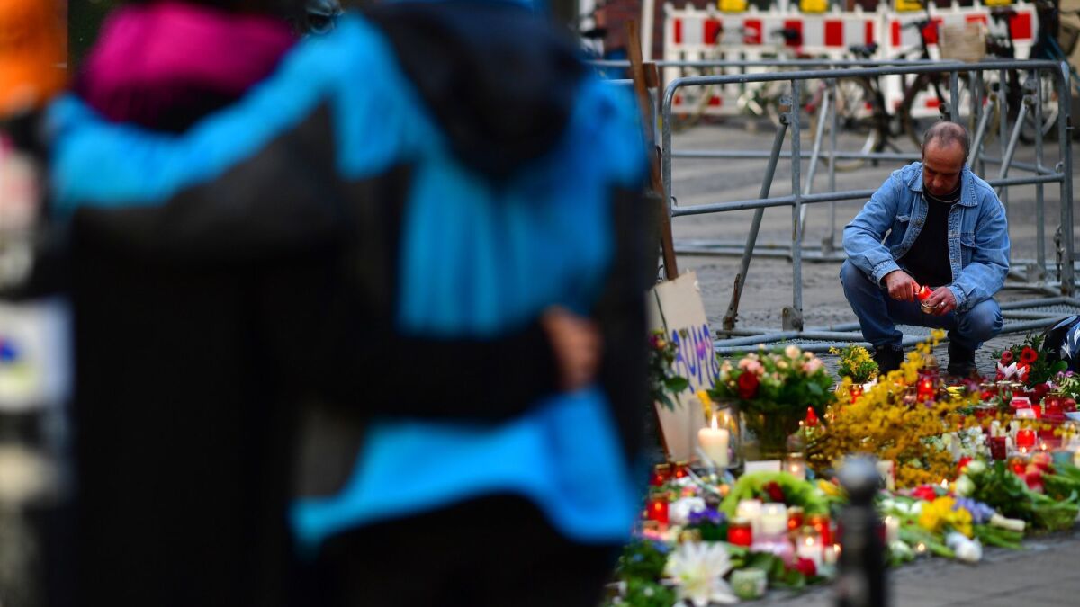 People leave flowers and candles at the scene in Muenster, Germany, where a van was driven into a crowd of people Saturday, leaving two dead and dozens injured.