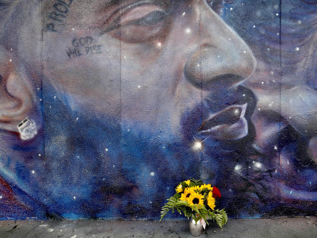 Flowers sit at the base of a mural of Nipsey Hussle at 5817 Crenshaw Blvd. (Luis Sinco / Los Angeles Times)