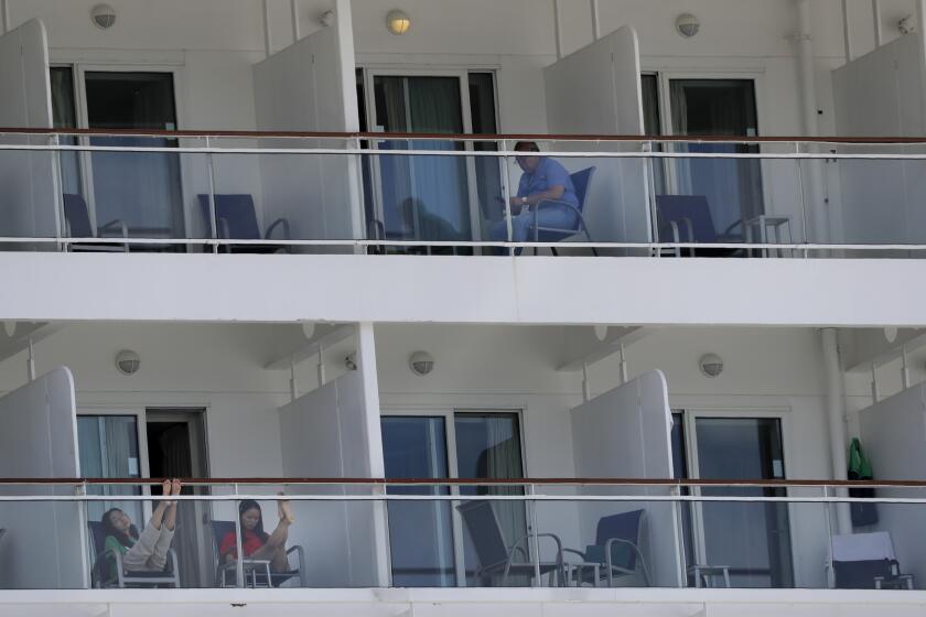 Fotografía del 8 de mayo de 2020 de personas a bordo del crucero Norwegian Epic atracado en Port Miami en Miami sentados en sus balcones. (AP Foto/Wilfredo Lee)