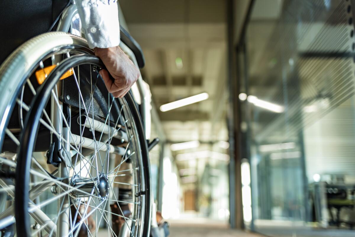 A man's hand on the wheel of a wheelchair 