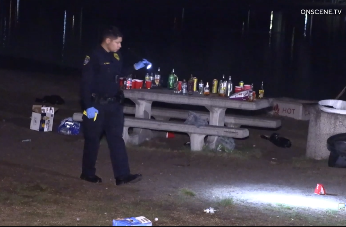 A San Diego police officer scans the scene after a Mission Bay party where a 16-year-old was shot during a fight.