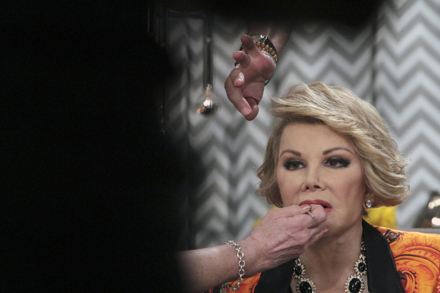 Makeup people fuss over Joan Rivers during a break in her show "Fashion Police" in early July. Rivers talks to the audience throughout the taping mostly from her chair, even as the crew changes sets or sets up shots, but she'll sometimes get up and engage audience members.