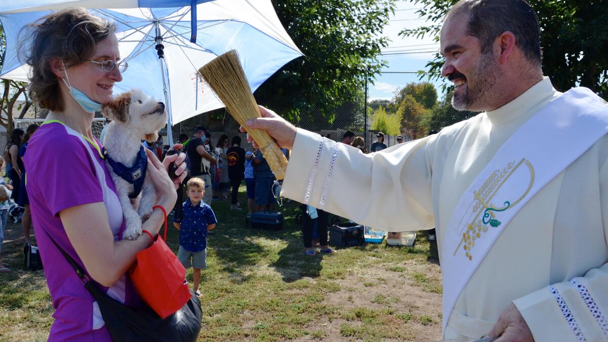 Deacon Francisco Javier Martin of St. Joachim Catholic Church in Costa Mesa sprinkles holy water on a dog.