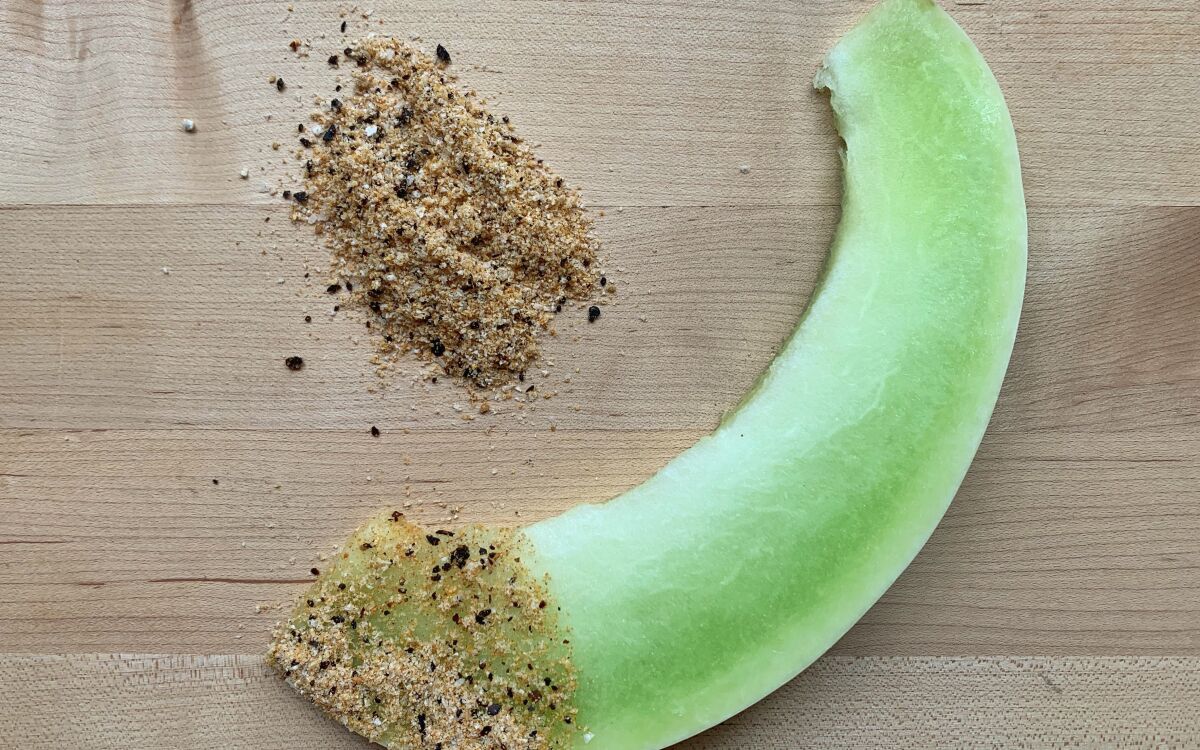 A slice of  honeydew melon dipped in a spice mix.