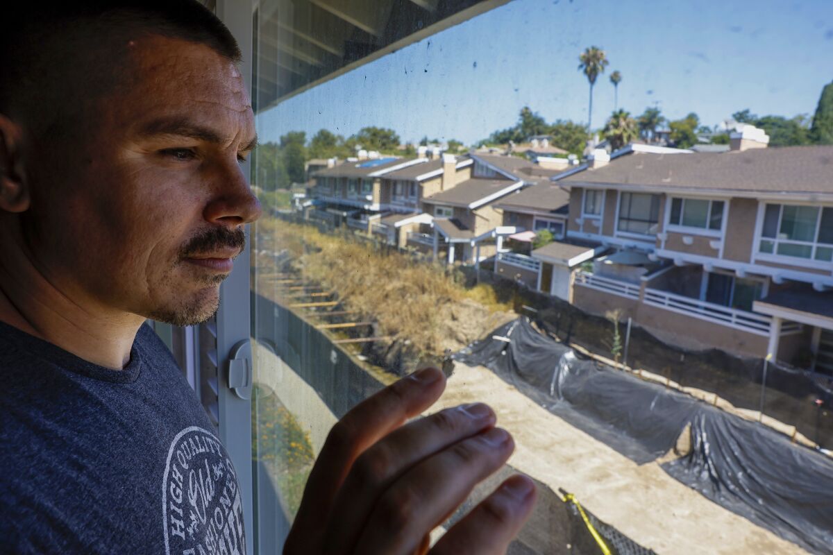 Justin Marinello looks out from the second floor of his condo to see an exposed flood channel 