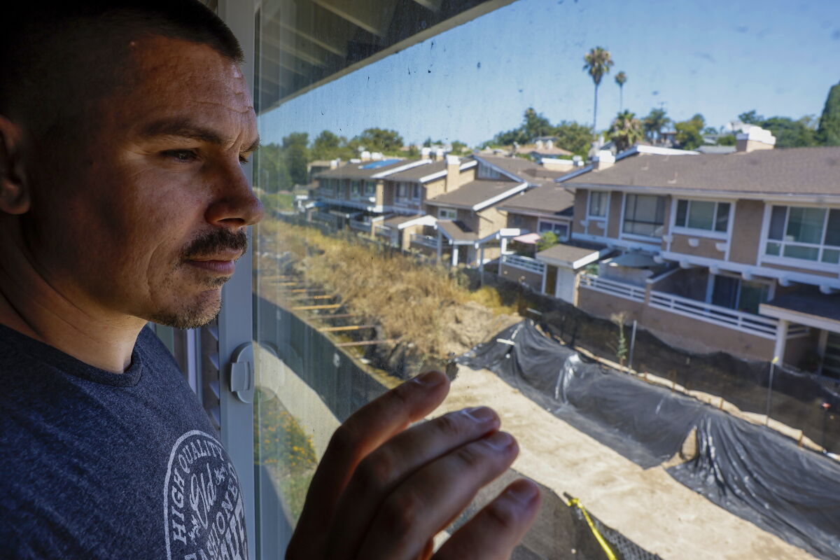 Justin Marinello looks out from the second floor of his condo to see an exposed flood channel