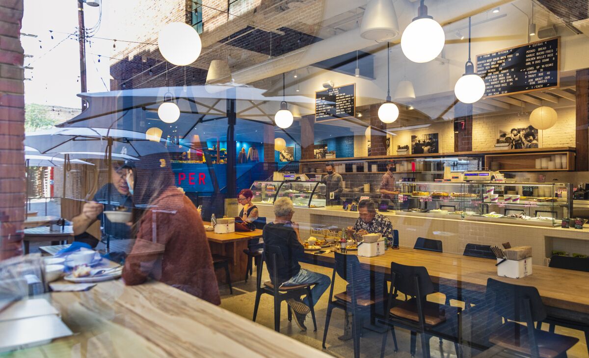 A dining room seen through glass in which outdoor umbrellas are reflected.