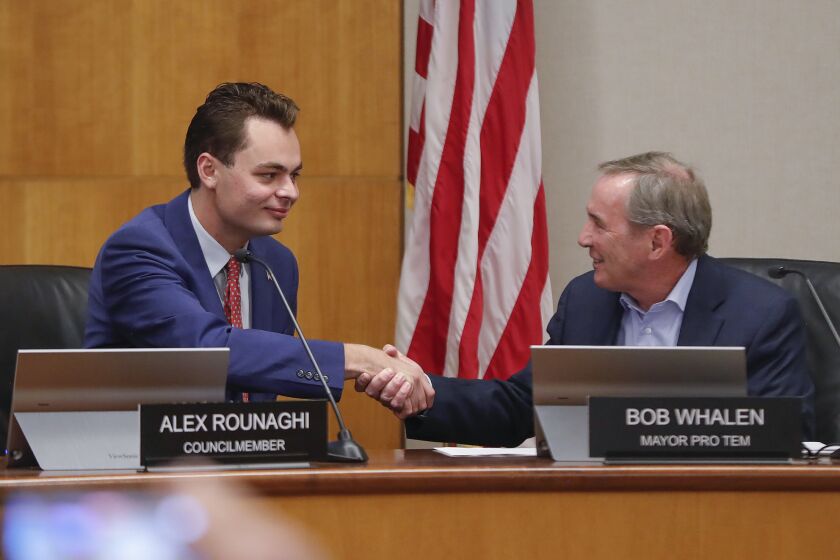 Newly sworn-in councilman Alex Rounaghi, left, takes his seat as he greets mayor pro-tem Bob Whalen during Laguna Beach city council meeting on Tuesday December 13th.