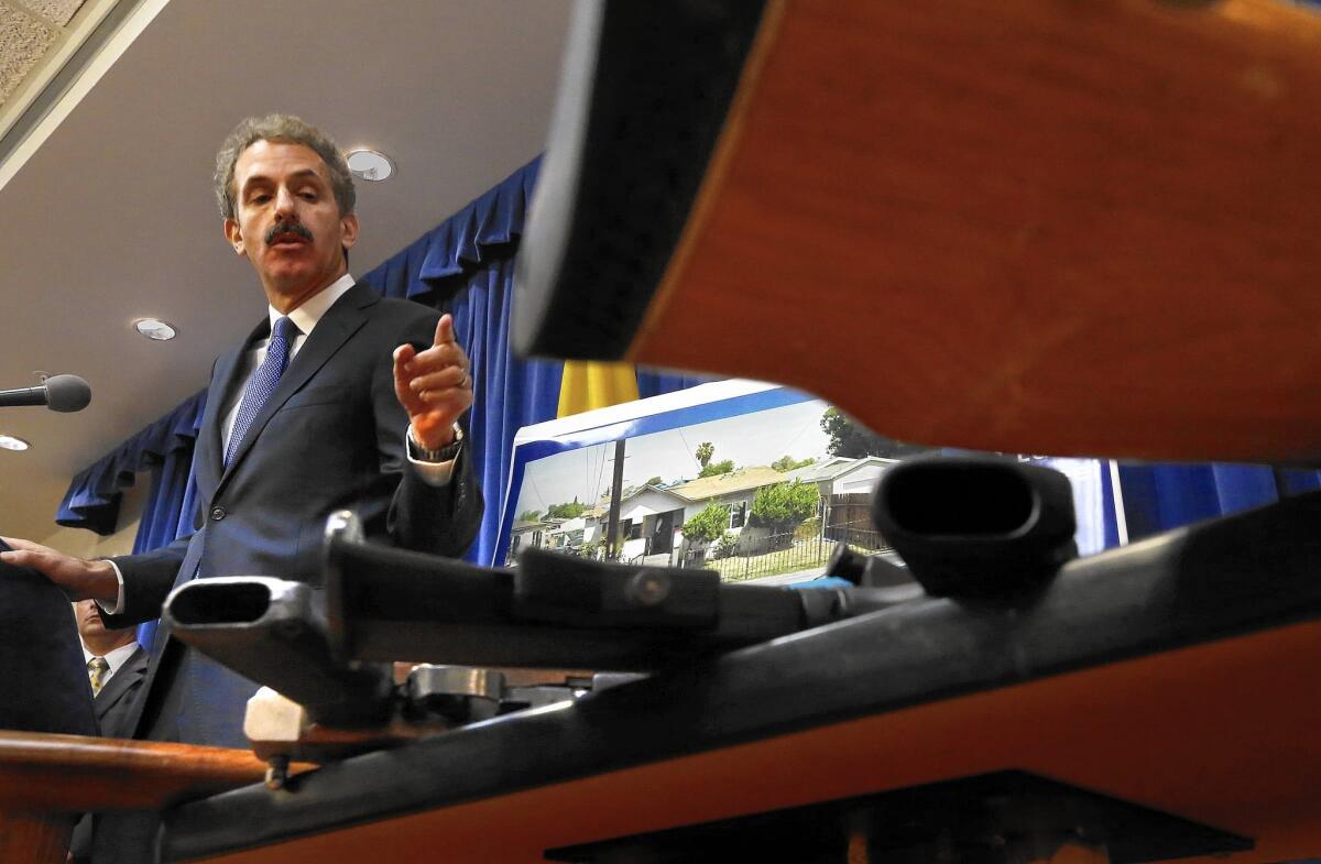 L.A. City Atty. Mike Feuer, at a news conference Tuesday, shows a table of weapons confiscated from a Watts home.