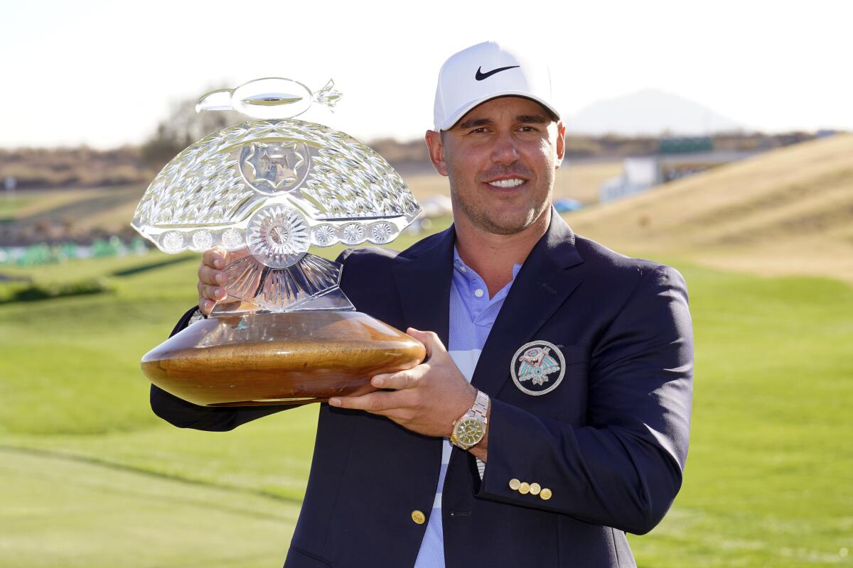 Brooks Koepka poses with the trophy after winning a PGA golf tournament on Sunday, Feb. 7, 2021.