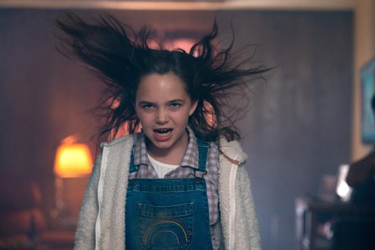 A young girl in overalls looks possessed