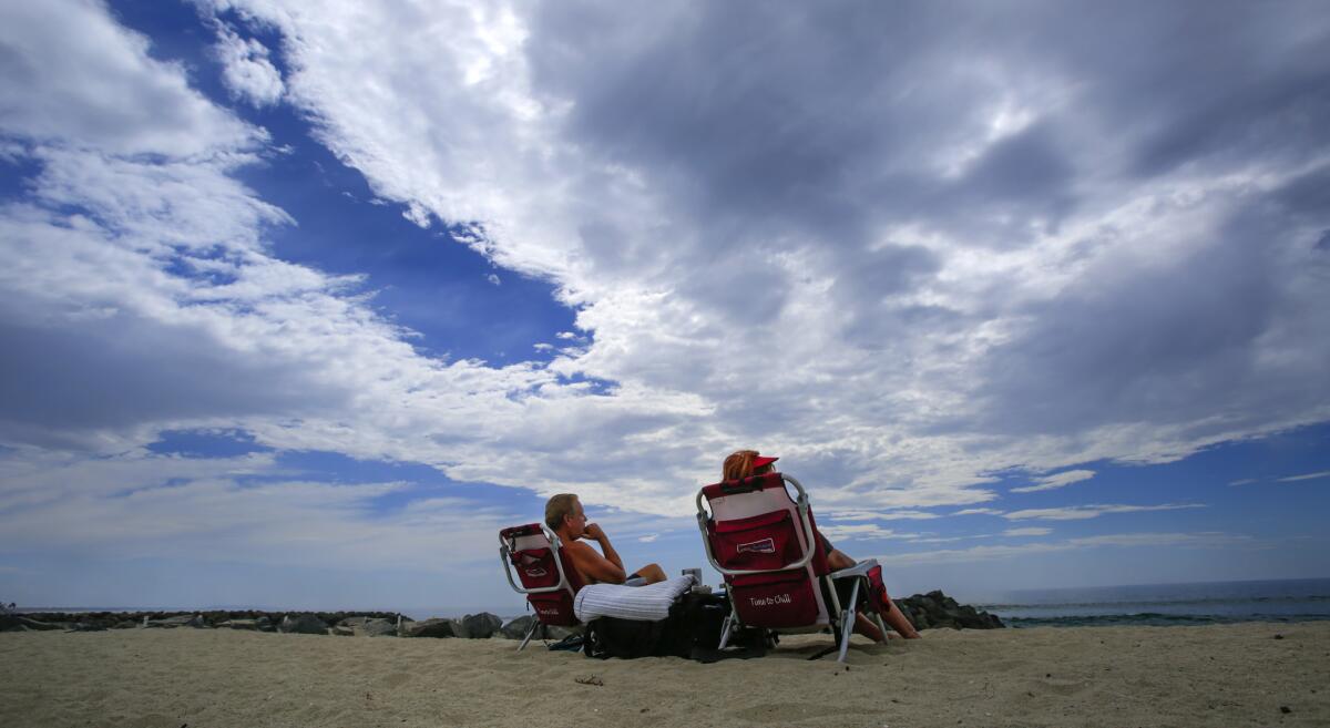 Two people sitting at Tamarack State Beach in Carlsbad. 