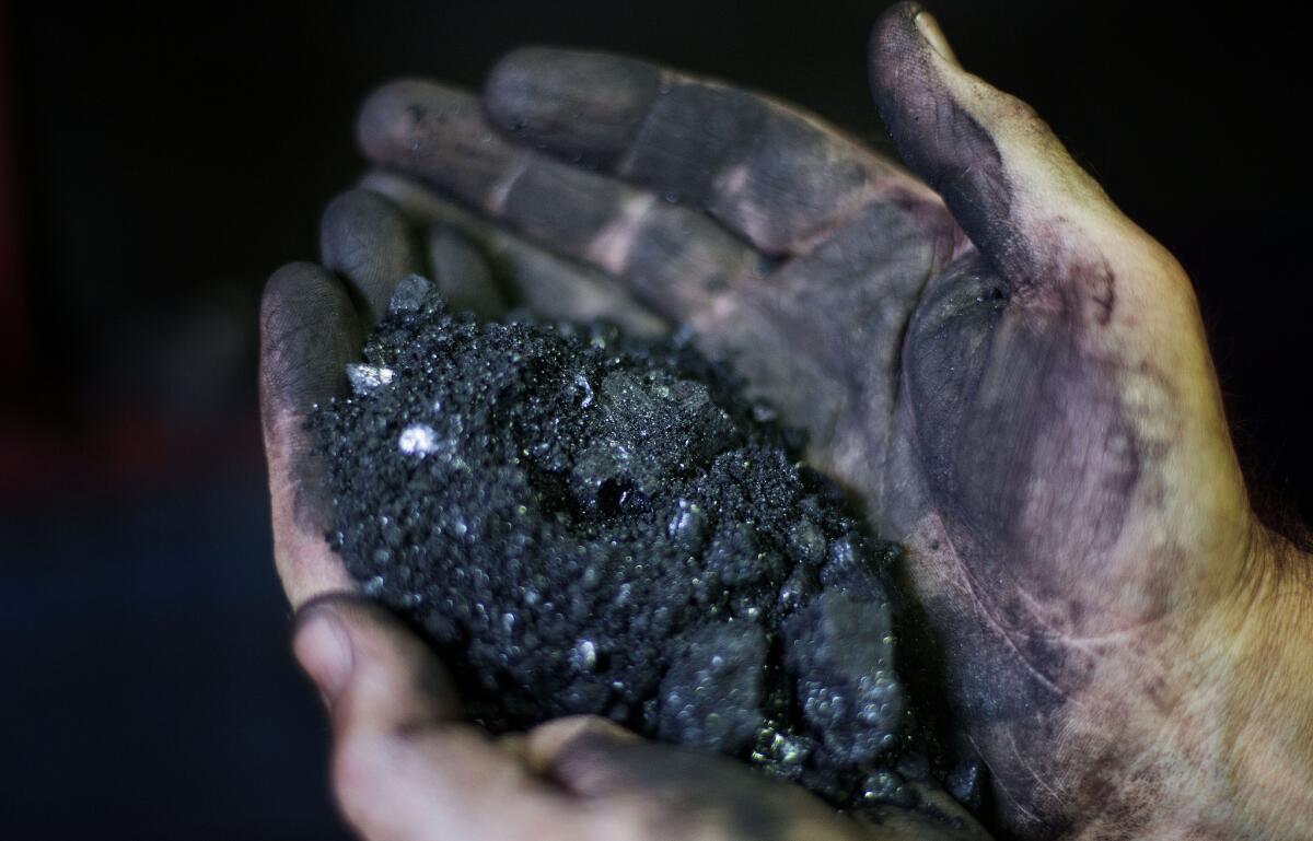 A miner holds coal at a processing plant in Welch, W.Va. in 2015. For the long-suffering communities that depend on coal, a recent Supreme Court ruling temporarily blocking greenhouse gas reductions was seen as a rare victory.