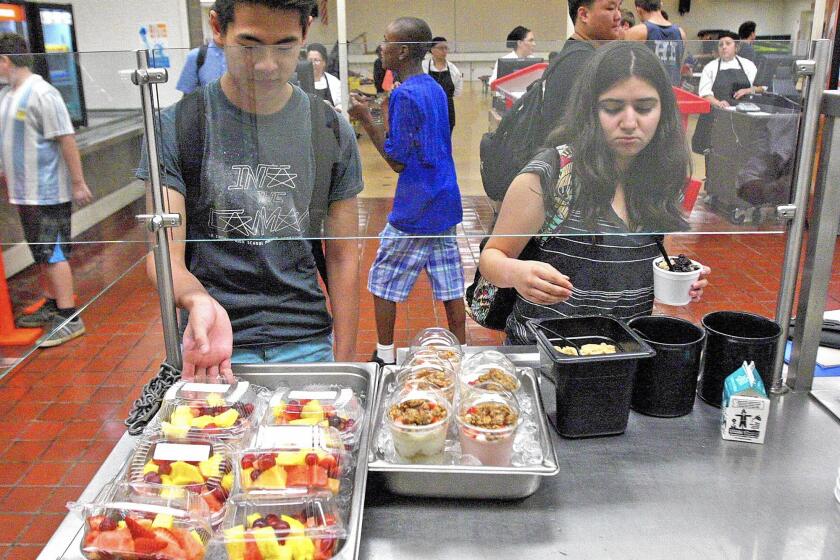 La Cañada High School student Bryan Dohi, 17, picks up a container of fresh fruit, and Ashley Medina, 15, tops off a cup of oatmeal in the cafeteria.