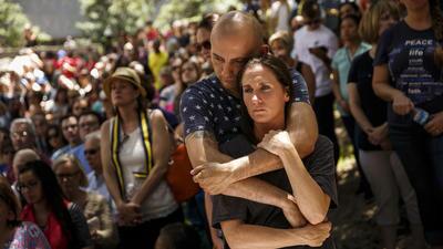 Daniel Bray embraces Emilie Bedell during an interfaith prayer event in Dallas for the victims of the mass shooting that killed five police officers and wounded seven others.