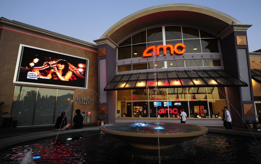Two people watch a big screen outside an AMC movie complex in Monterey Park in 2012.