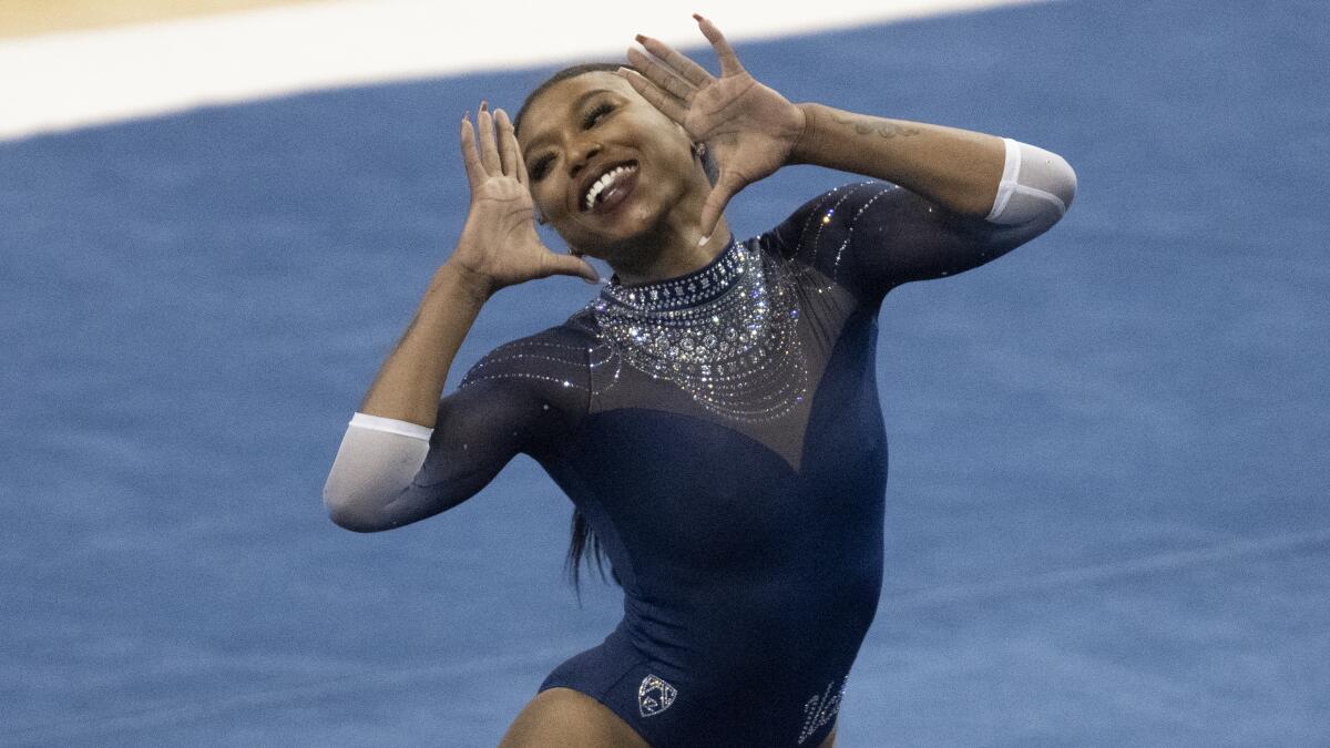 UCLA's Nia Dennis holds her hands up on either side of her face during a floor routine.
