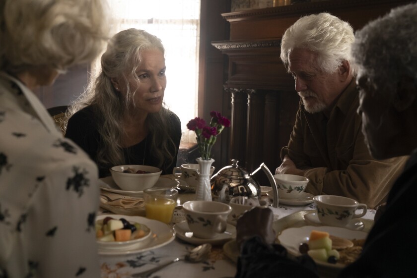 Four people sit around a table set with food.