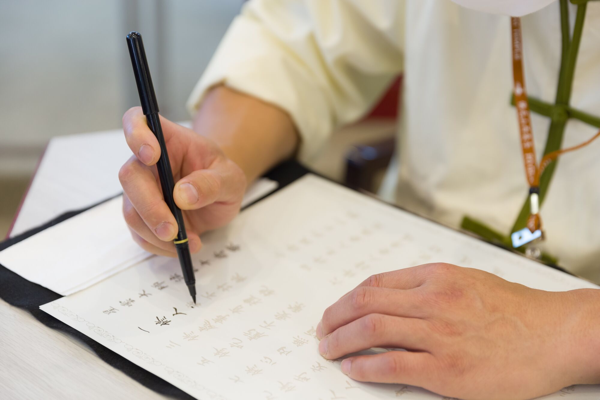 A closely up a hand holding a brush writing Chinese calligraphy