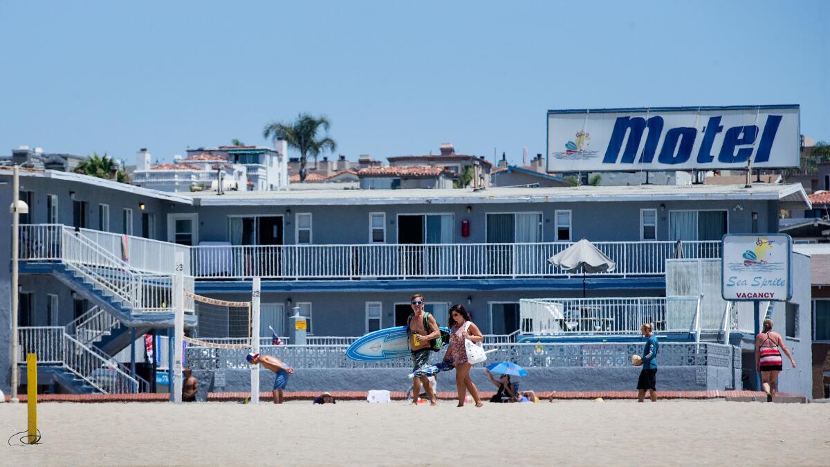 Surfers walk past the Sea Sprite Motel in Hermosa Beach on Aug. 11, 2016.