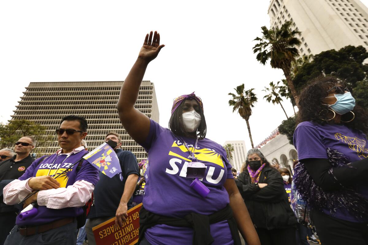Patty Pitchford, center, takes part in a moment of silence for victims of COVID-19 during a rally of  SEIU Local 721.