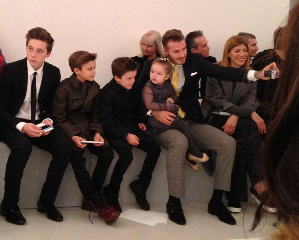 David Beckham takes a photo of his four children in the front row before the Victoria Beckham's show. Daughter Harper is in his lap, and sons Brooklyn, left, Romeo and Cruz sit alongside.