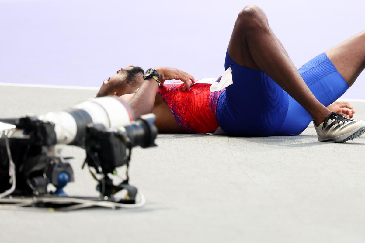 American Noah Lyles lies on the track beside a row of cameras