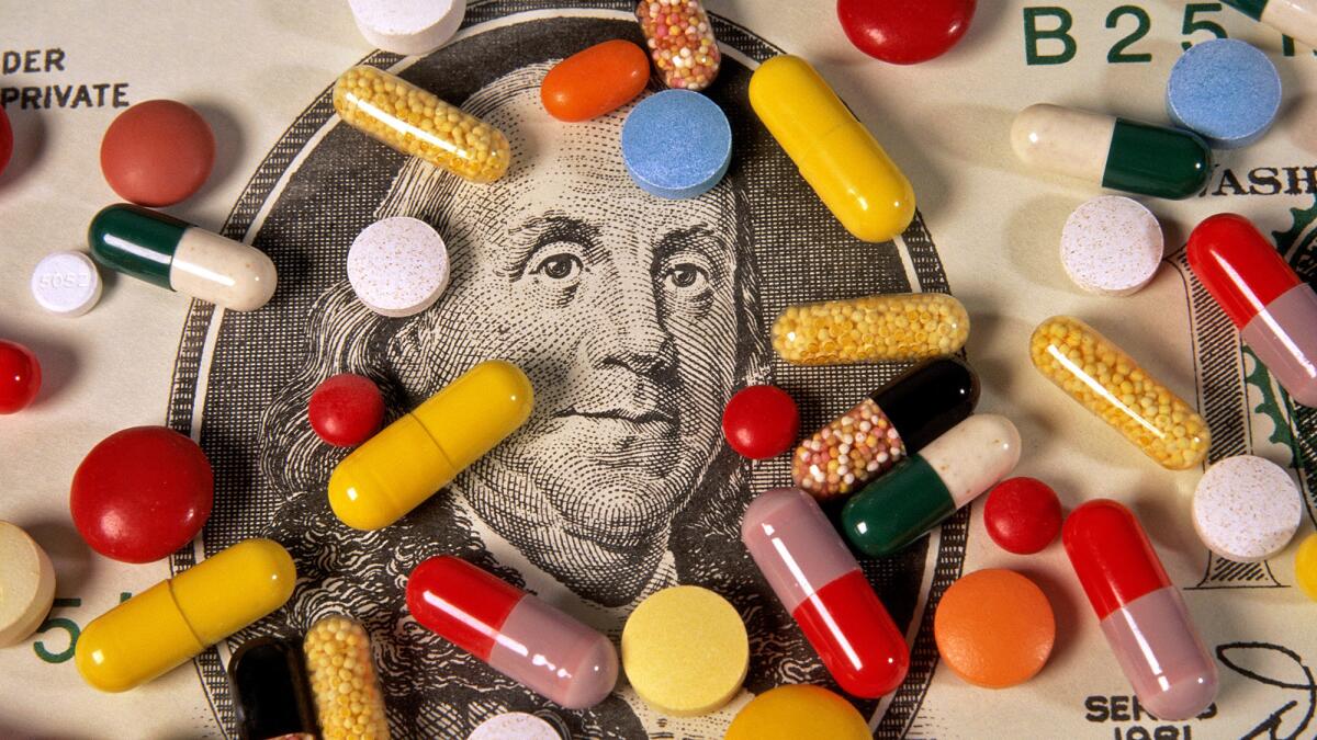 An assortment of pills sits on top of a $100 bill around the portrait of Benjamin Franklin