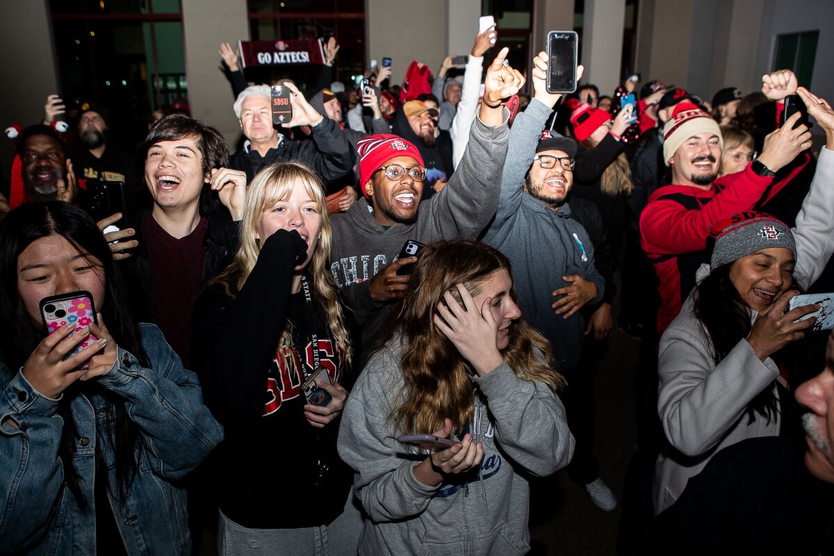 San Diego State fans cheer as buses carrying SDSU players and coaches arrive on campus in front of Fowler Athletics Center.