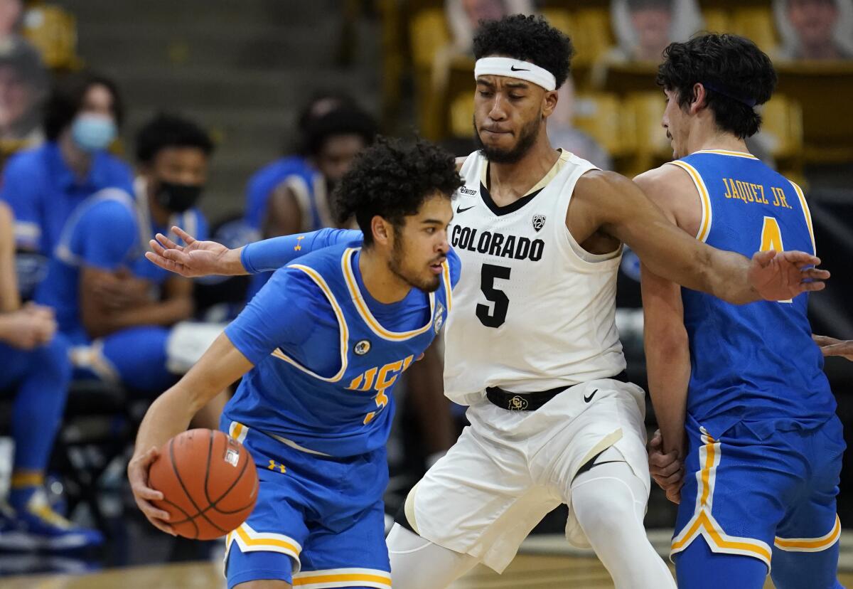 UCLA guard Johnny Juzang is defended by Colorado guard D'Shawn Schwartz.