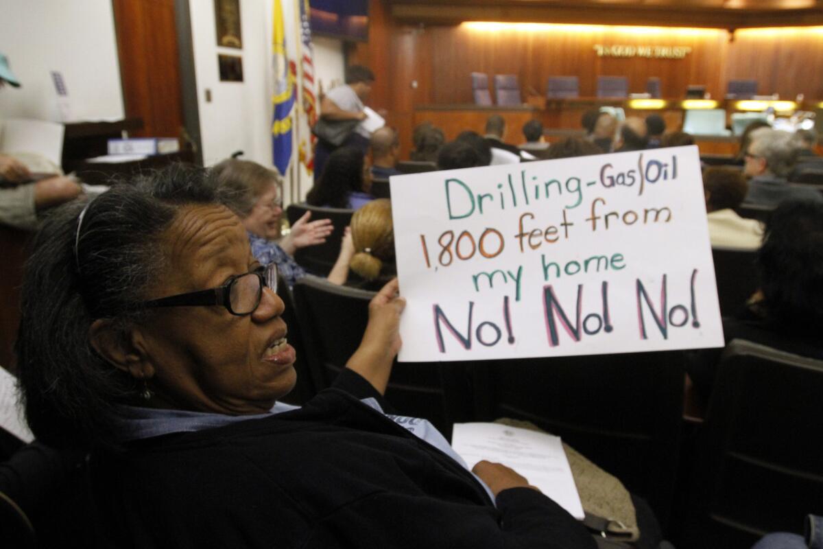 Before a Carson City Council meeting in March, Frances Haywood holds a sign protesting new oil and gas production. California Resources, which was seeking to drill 200 wells to extract oil from the Dominguez Oil Field, announced Monday that it is dropping the project.