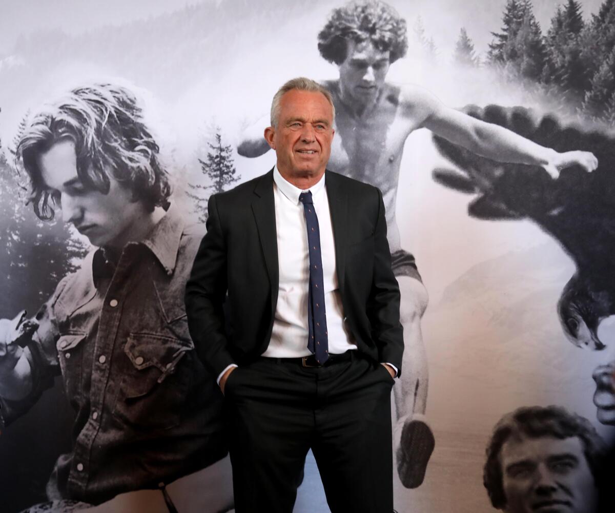 Robert F. Kennedy Jr. poses in front of a mural of images of himself as a young man.