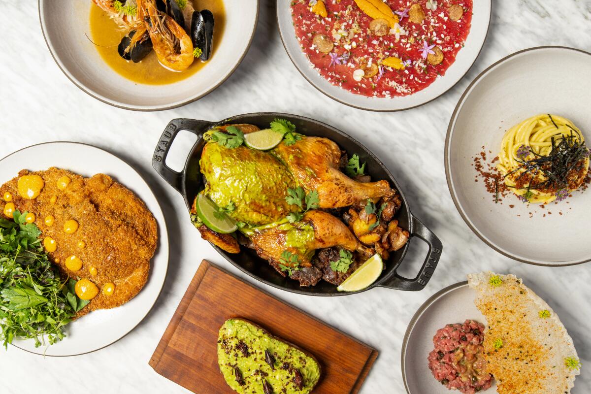 An overhead photo of an array of dishes atop marble. At the center is a spatchcocked chicken.