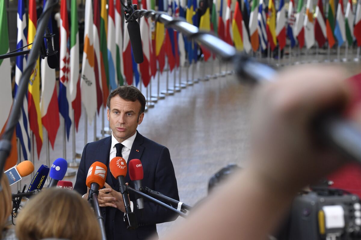 French President Emmanuel Macron speaks in front of a row of European flags.