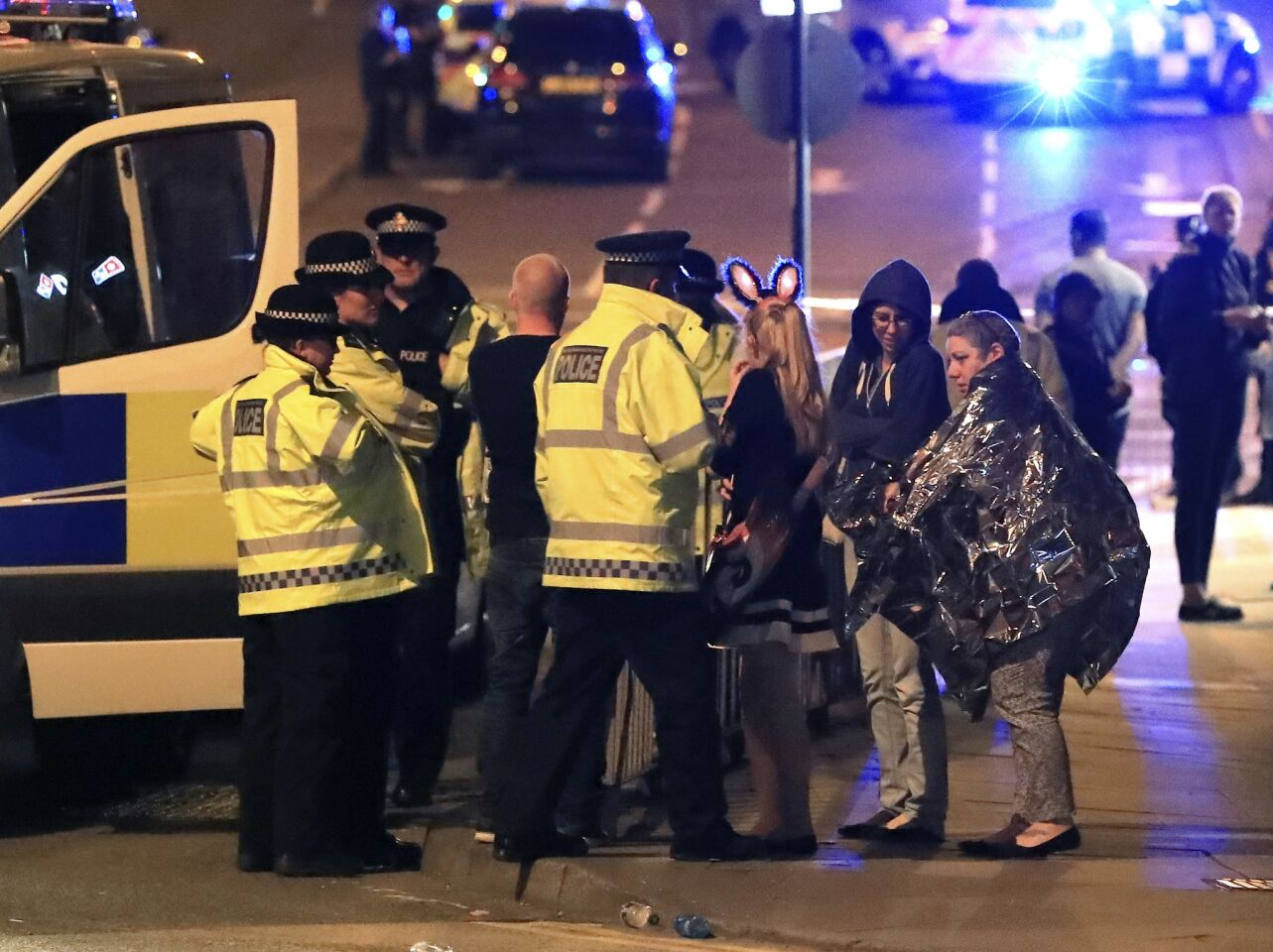 Emergency services personnel speak to people outside Manchester Arena after reports of an explosion at the venue Monday night.