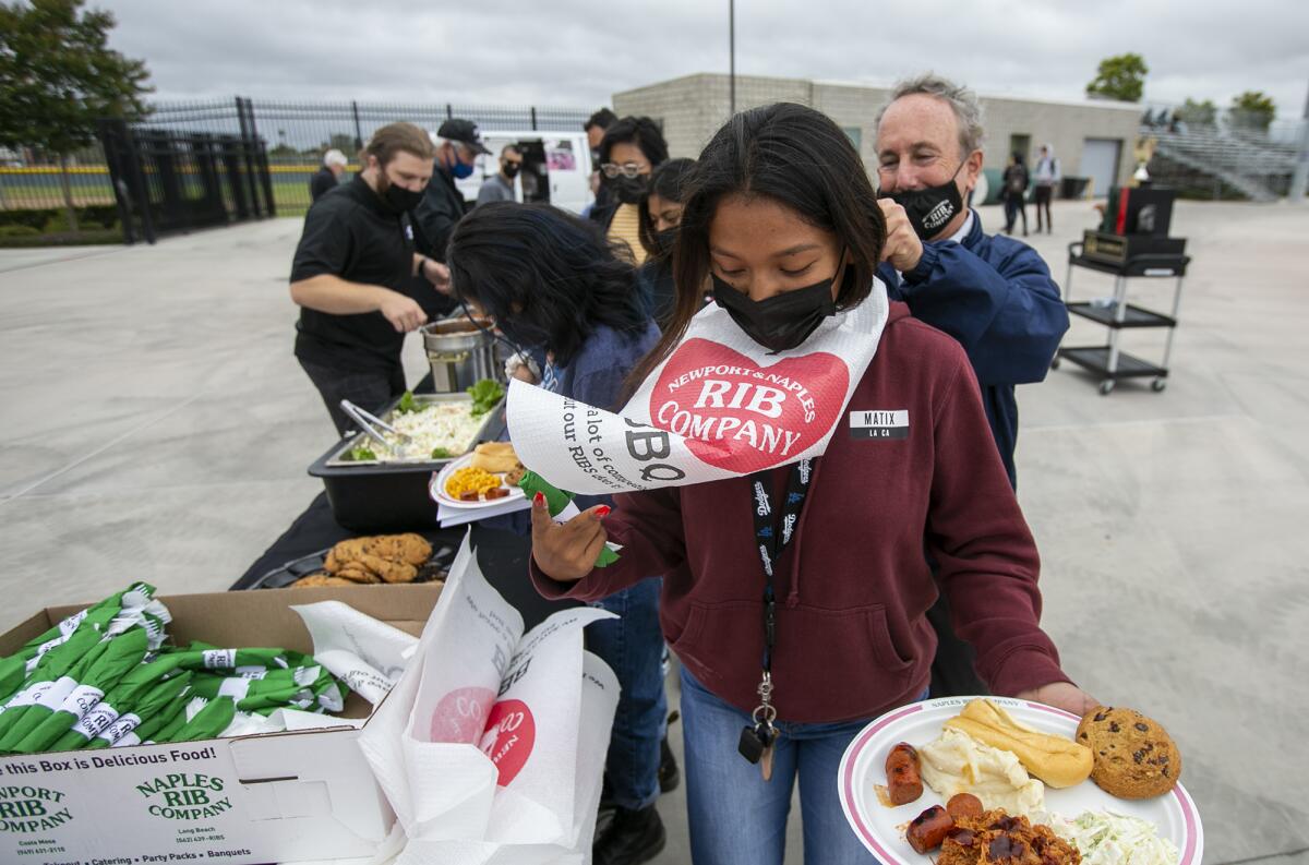 John Ursini of Newport Rib Co. helps Yessica Najera with a bib during the All-Sports Cup lunch June 7.