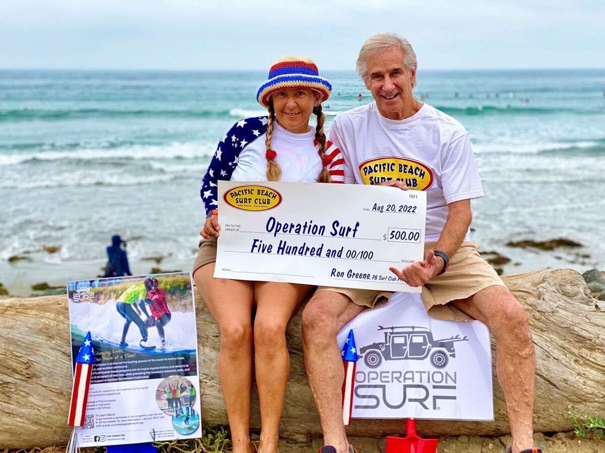 Surfer Roxy Gunther and Pacific Beach Surf Club President Ron Greene with a $500 donation to Operation Surf on Aug. 20.