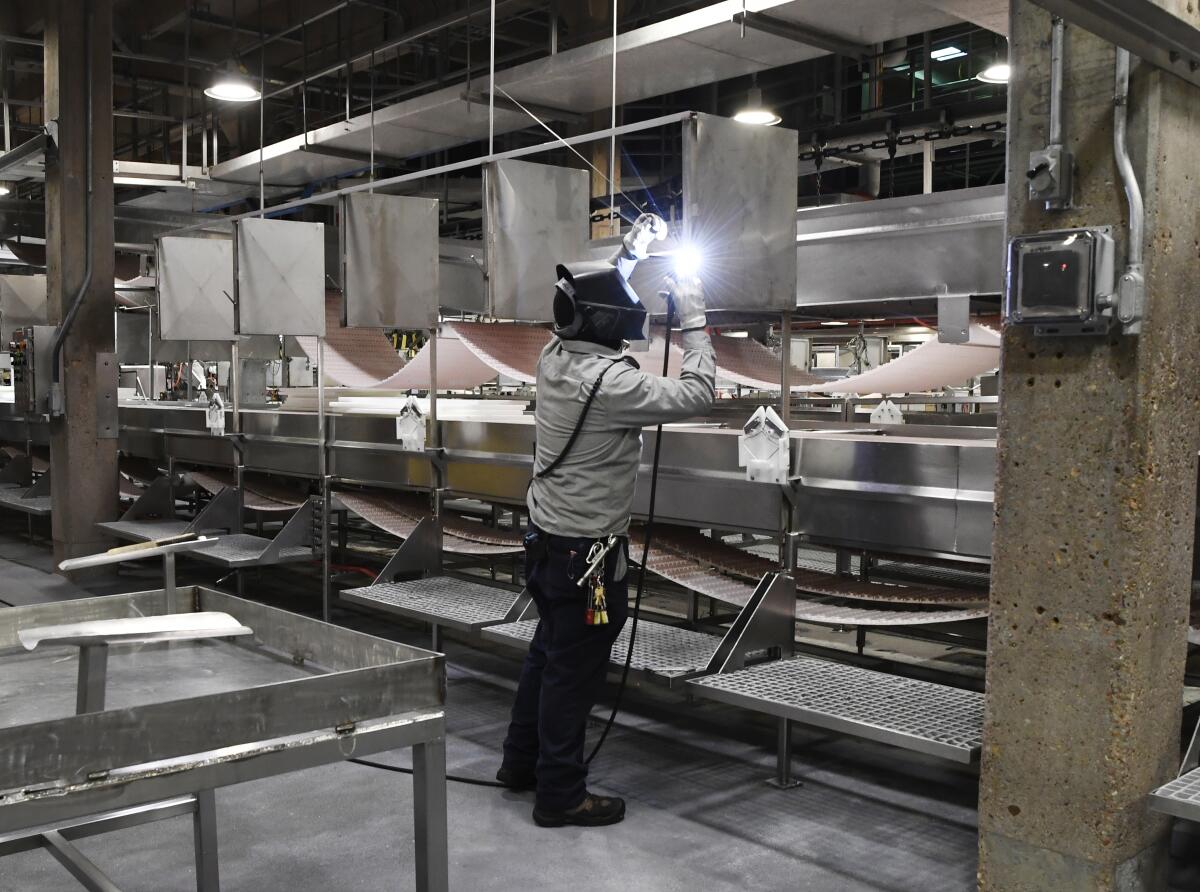 A welder in protective gear working inside a meat plant.