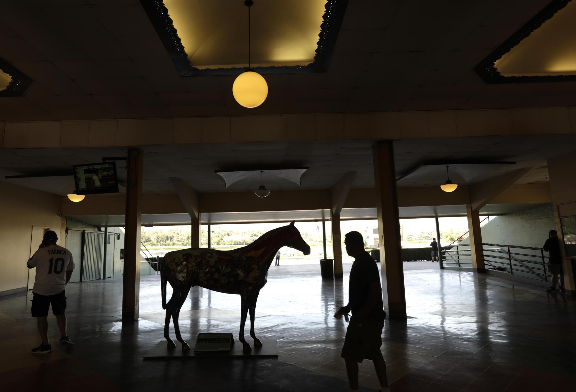 Visitors make their way past a sculpture of a horse at Santa Anita Park during the 2021 fall meeting.