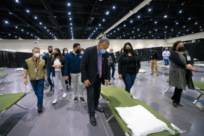 San Diego, CA - March 27: At San Diego Convention Center on Saturday, March 27, 2021 in San Diego, CA., Congressman Juan Vargas prepared to take a close look at one of the sleeping cots in an area where the girls will sleep. Along with Vargas are San Diego Mayor Todd Gloria, Representative Sara Jacobs and San Diego Supervisor Nora Vargas. The girls between the ages of 13-17 will be separated in sleeping areas that will host up to 50-girls per pod. (Nelvin C. Cepeda / The San Diego Union-Tribune)