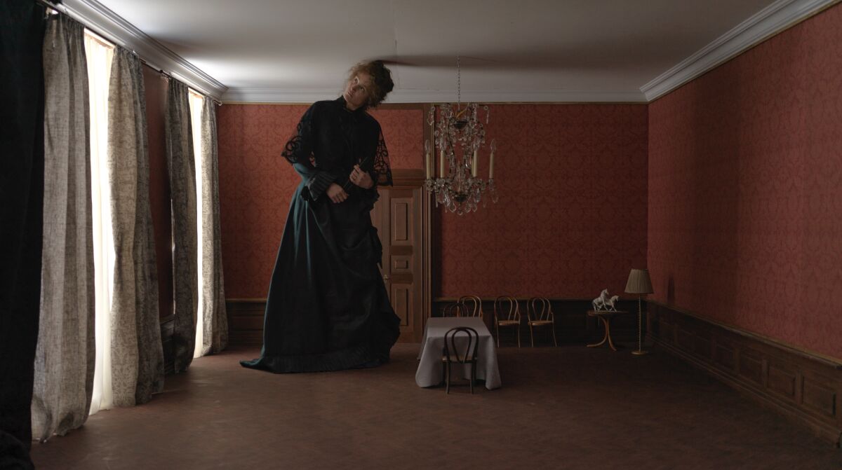 A woman appears trapped in an ornate room that is too small for her. 