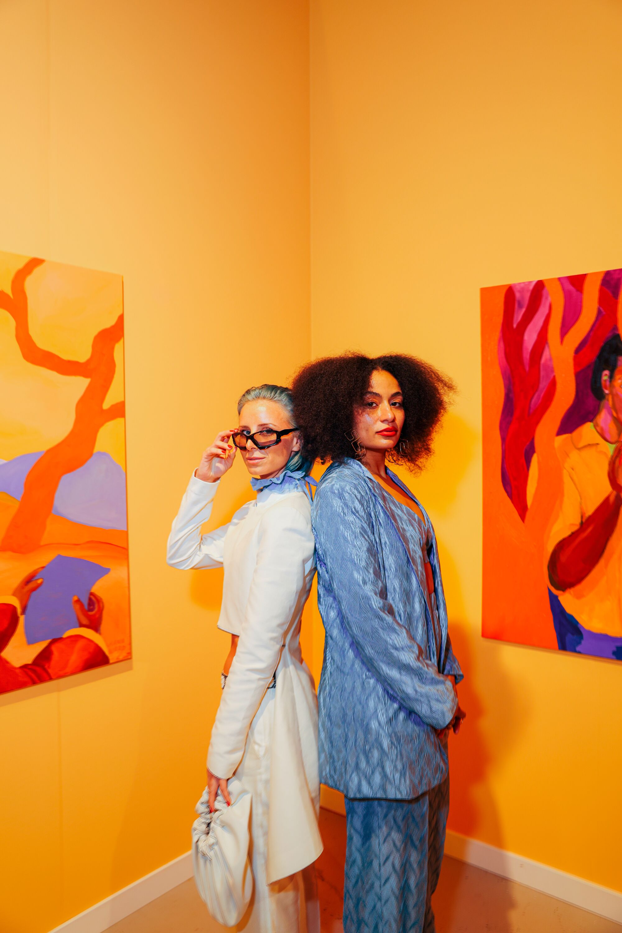 Two people pose in front of artwork.