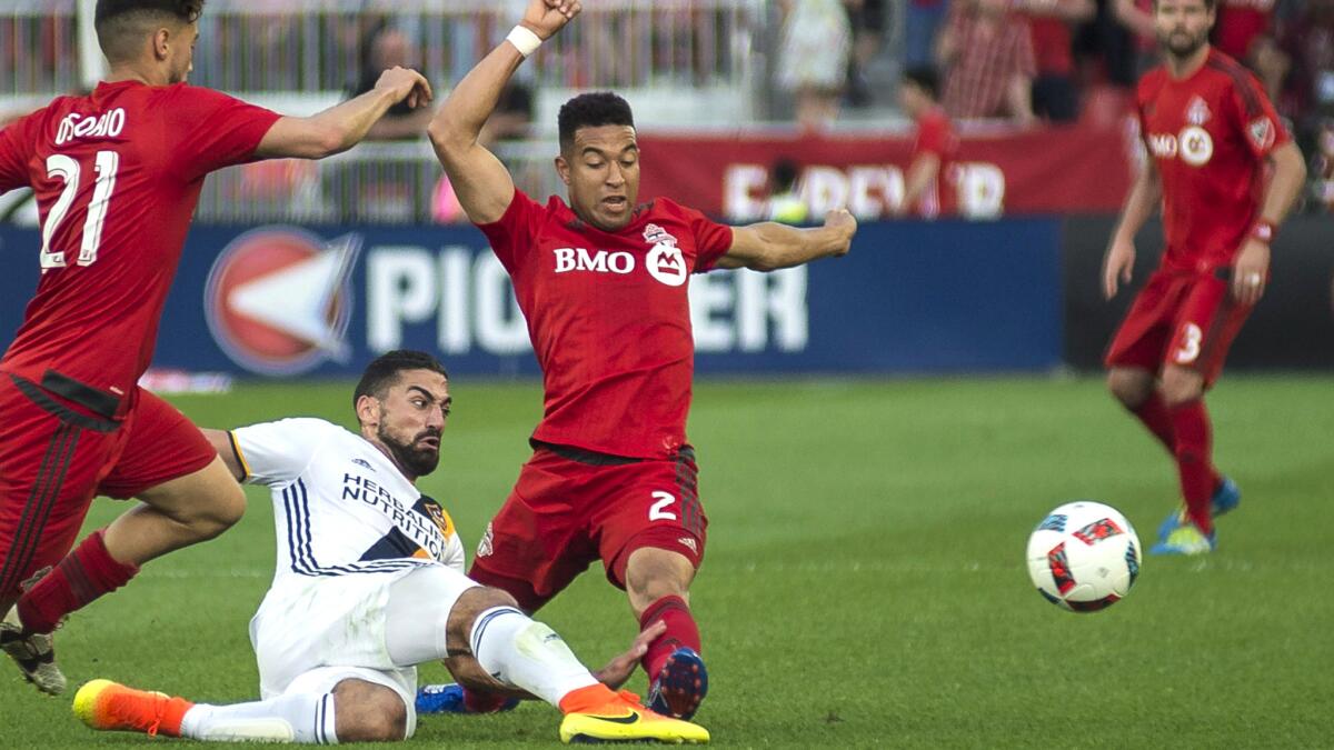 Galaxy midfielder Sebastian Lletget beats Toronto FC's Jonathan Osorio (21) and Justin Morrow to the ball during the first half Saturday in Toronto.