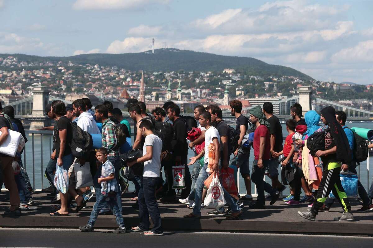 Hundreds of refugees walk on the Elisabeth Bridge after leaving the transit zone of the Budapest main train station on Friday intent on walking to the Austrian border. They were part of an estimated 2,000 migrants stuck in makeshift camps after railway authorities had blocked them from boarding trains to Austria and Germany.