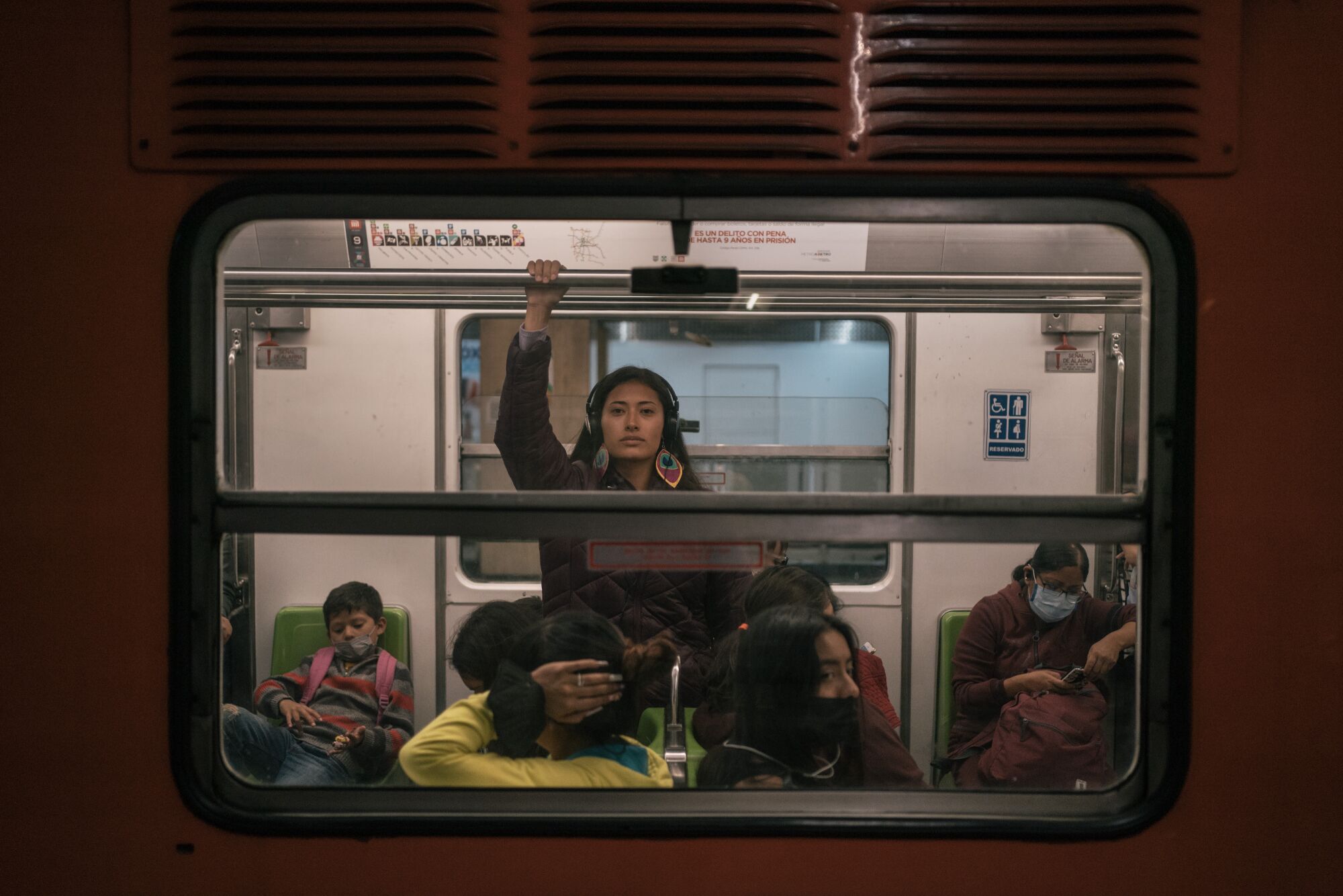 A woman holding onto a rail looks out from a subway train window