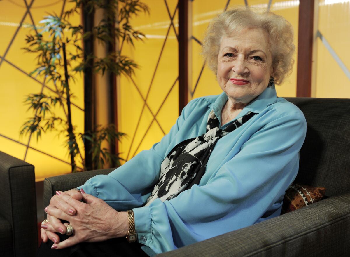 Betty White sitting in a chair wearing a blue blouse