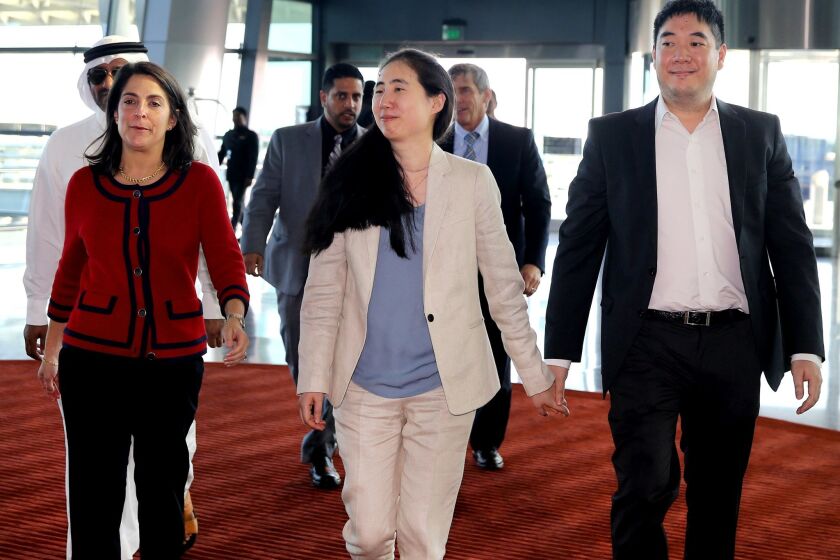 Escorted by U.S. Ambassador to Qatar Dana Shell Smith, left, Grace and Matthew Huang walk to their departure gate at Hamad International Airport in Doha on Wednesday.