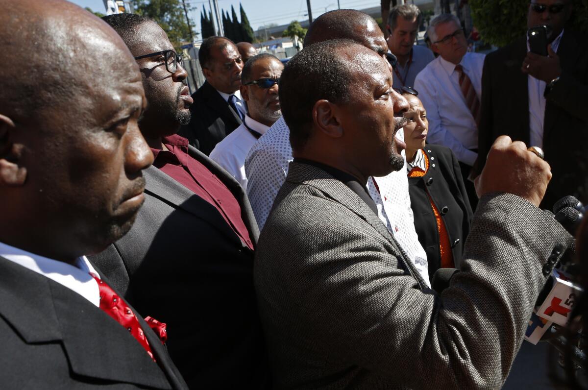Pastor Kelvin Sauls, far left, from Holman United Methodist Church, listens as community activist Najee Ali denounces recent behavior by Black Lives Matters members against L.A. Mayor Eric Garcetti.
