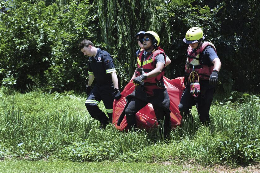 Rescuers carry the body of a flood victim that was retrieved from the Jukskei river in Johannesburg, Sunday, Dec. 4, 2022. At least nine people have died while eight others are still missing in South Africa after they were swept away by a flash flood along the Jukskei river in Johannesburg, rescue officials said Sunday. (AP Photo)