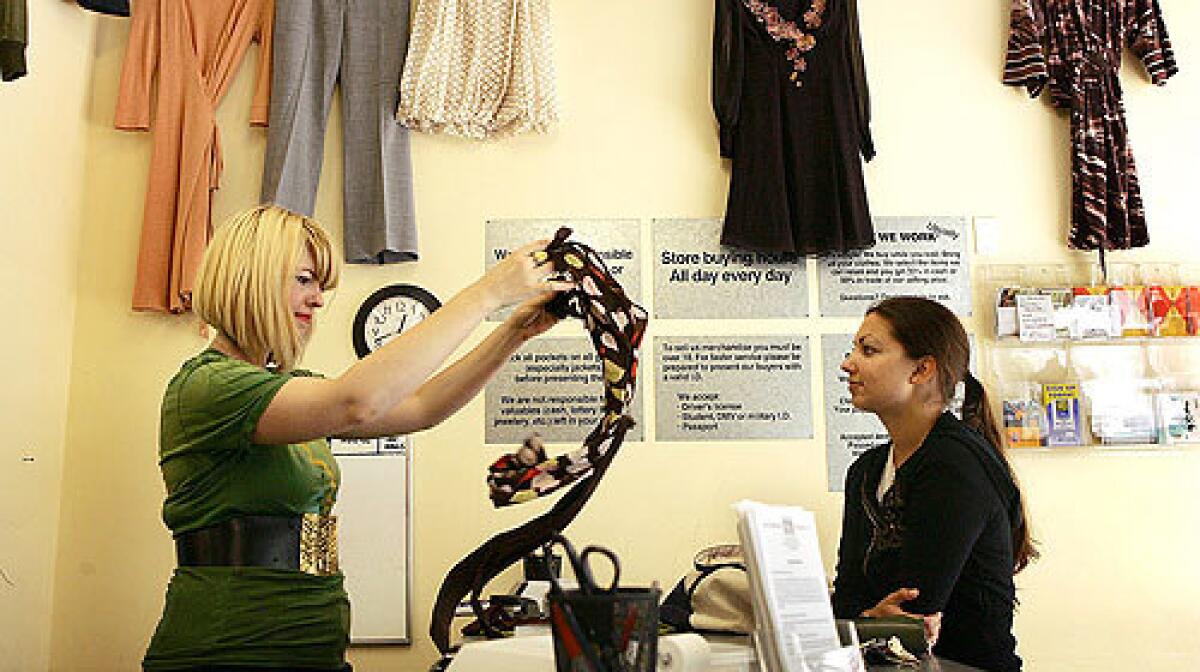 Crossroads Trading Co. manager Christie Cook, left, evaluates an item offered for resale by Amber Sheikh.
